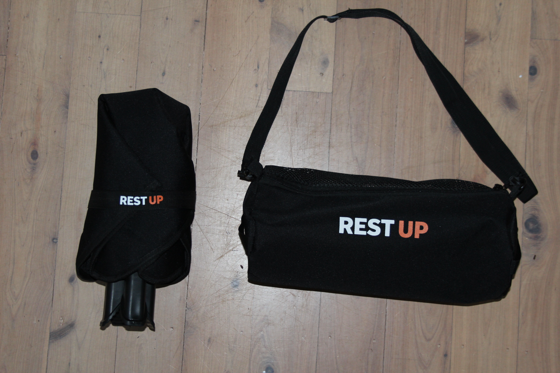 Restup folded beside its carry bag on a timber floor